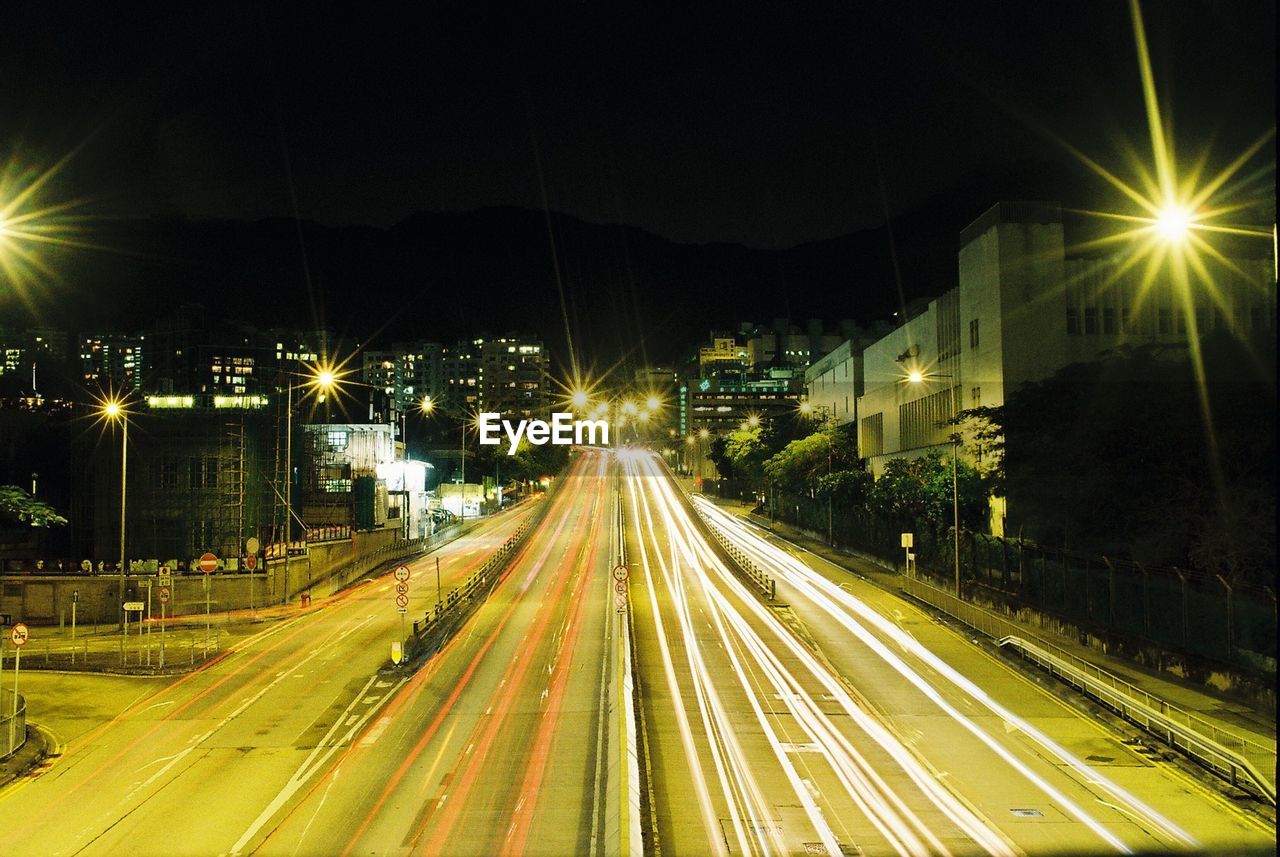 Light trails on road along illuminated street lights at night