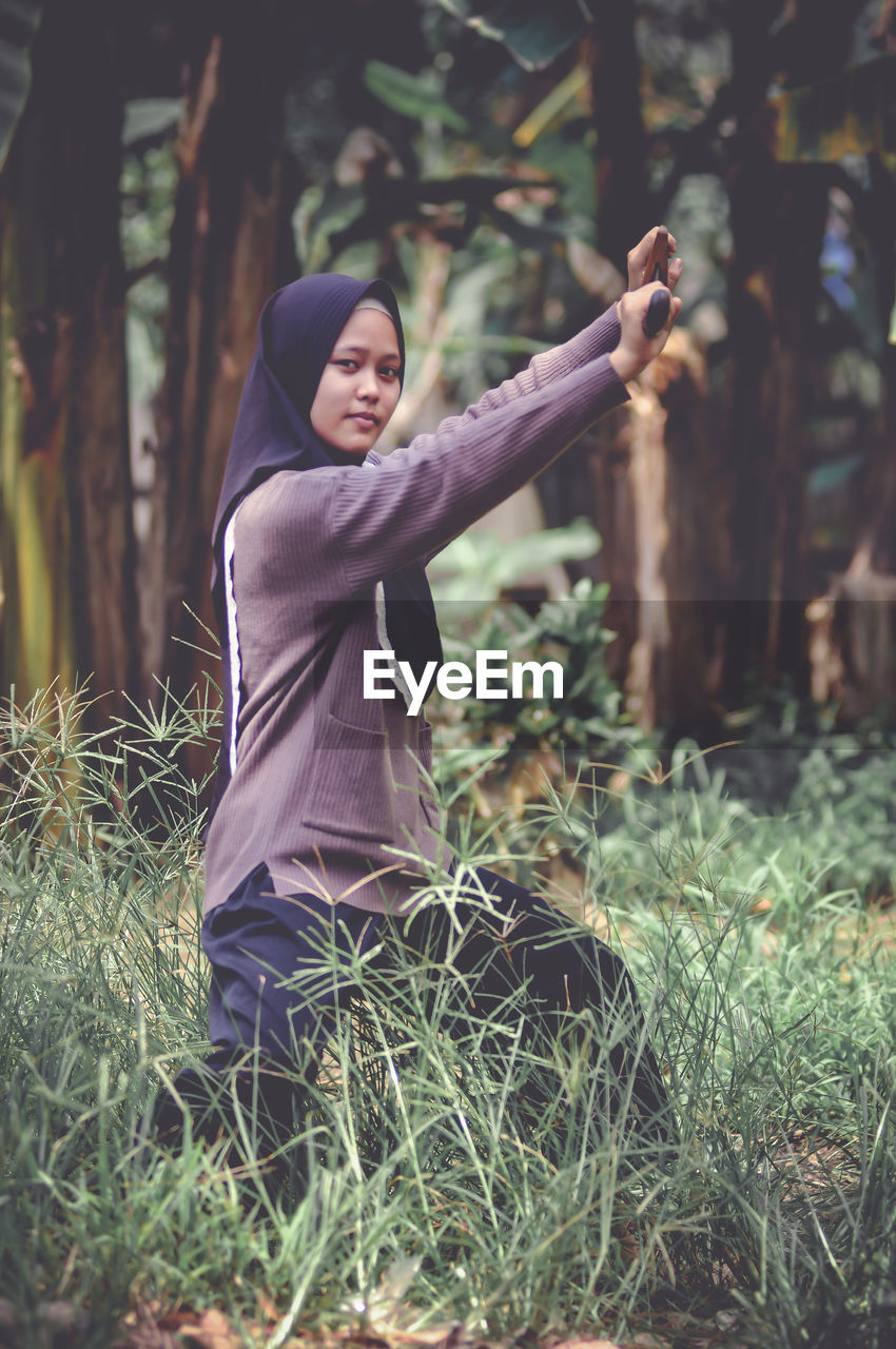 Side view of woman with arms raised standing on field