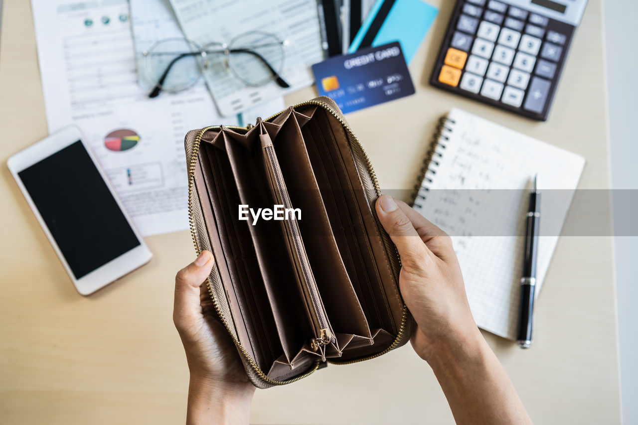 Cropped hands of woman holding purse at table in office