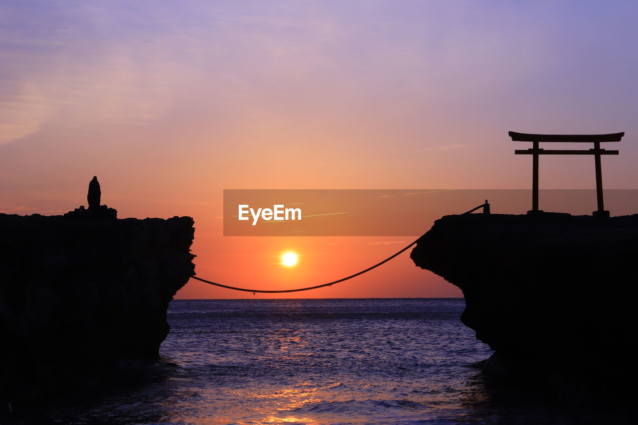 Silhouette of cliff at seaside during sunset