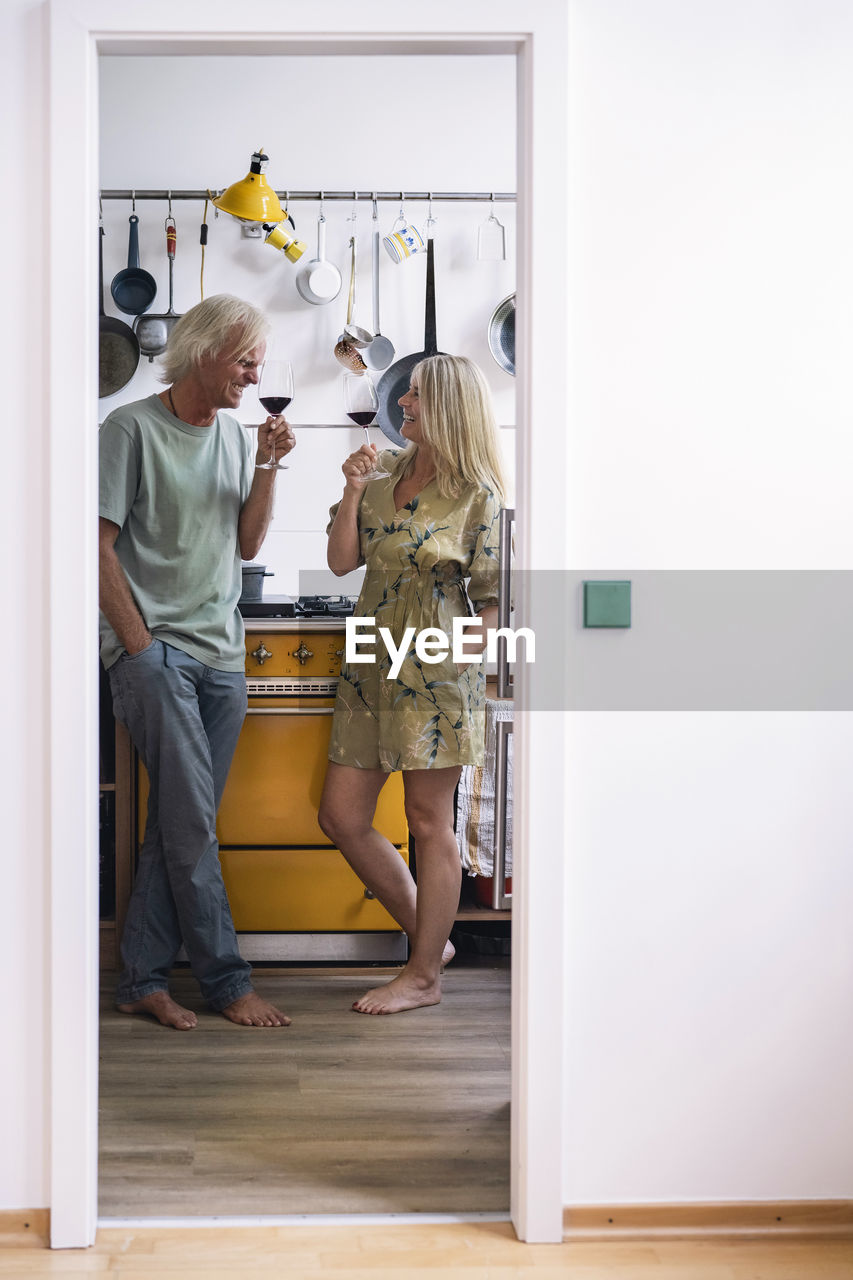 Happy couple drinking red wine in kitchen