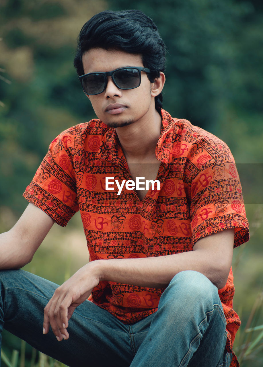 Young man wearing sunglasses sitting outdoors