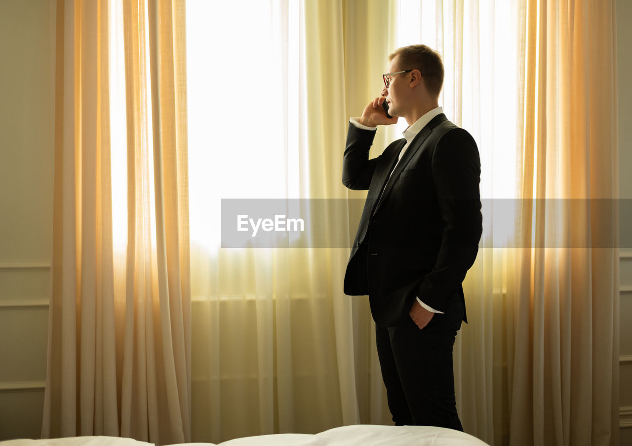 Modern adult businessman calling by phone in hotel