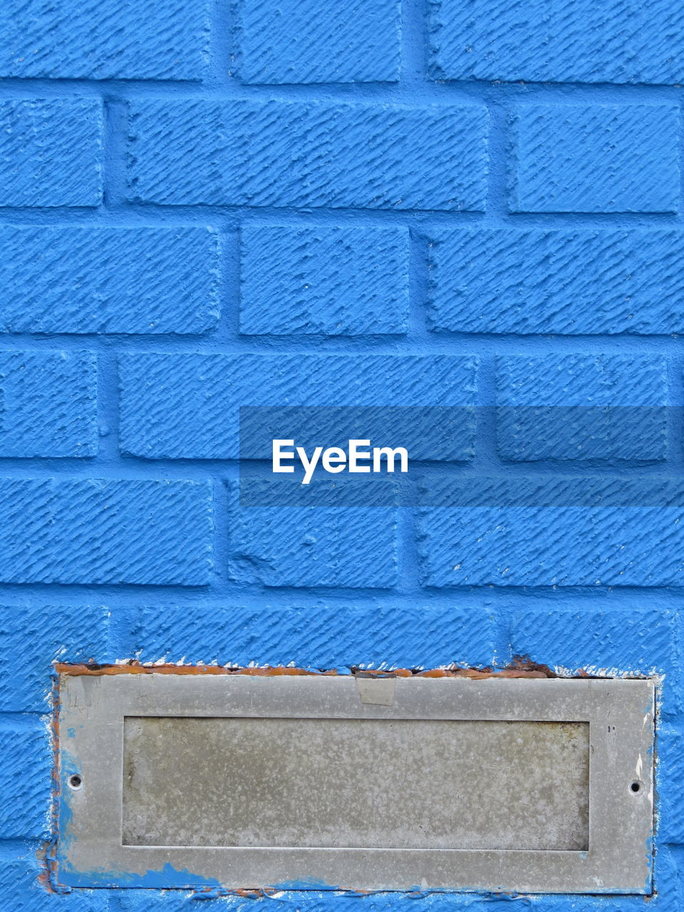Close-up view of blue wall with metal letterbox