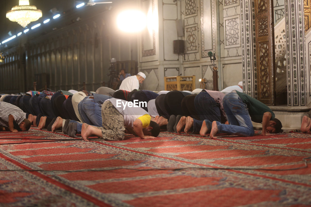 Men praying in illuminated mosque