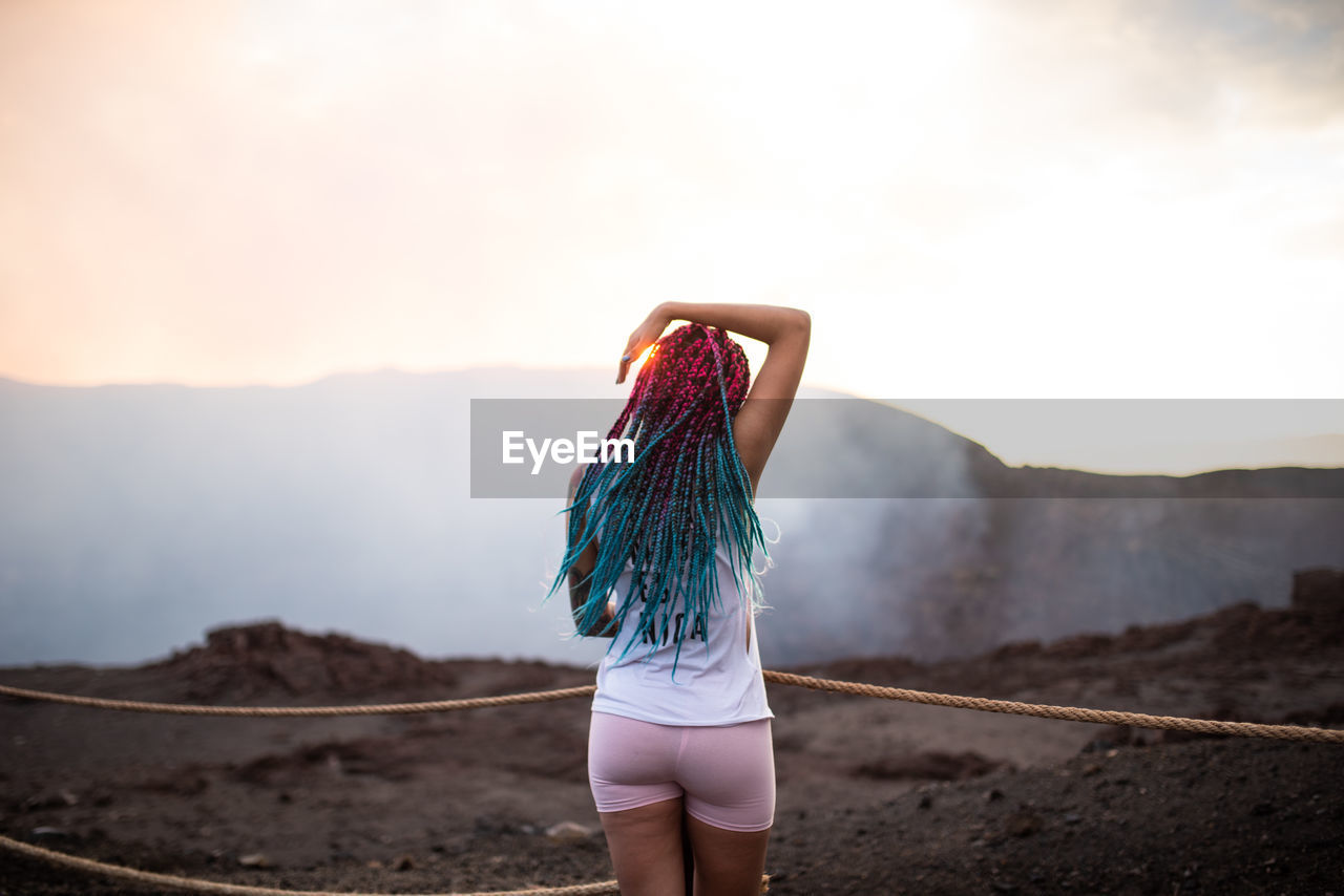 Rear view of woman looking at mountains against sky