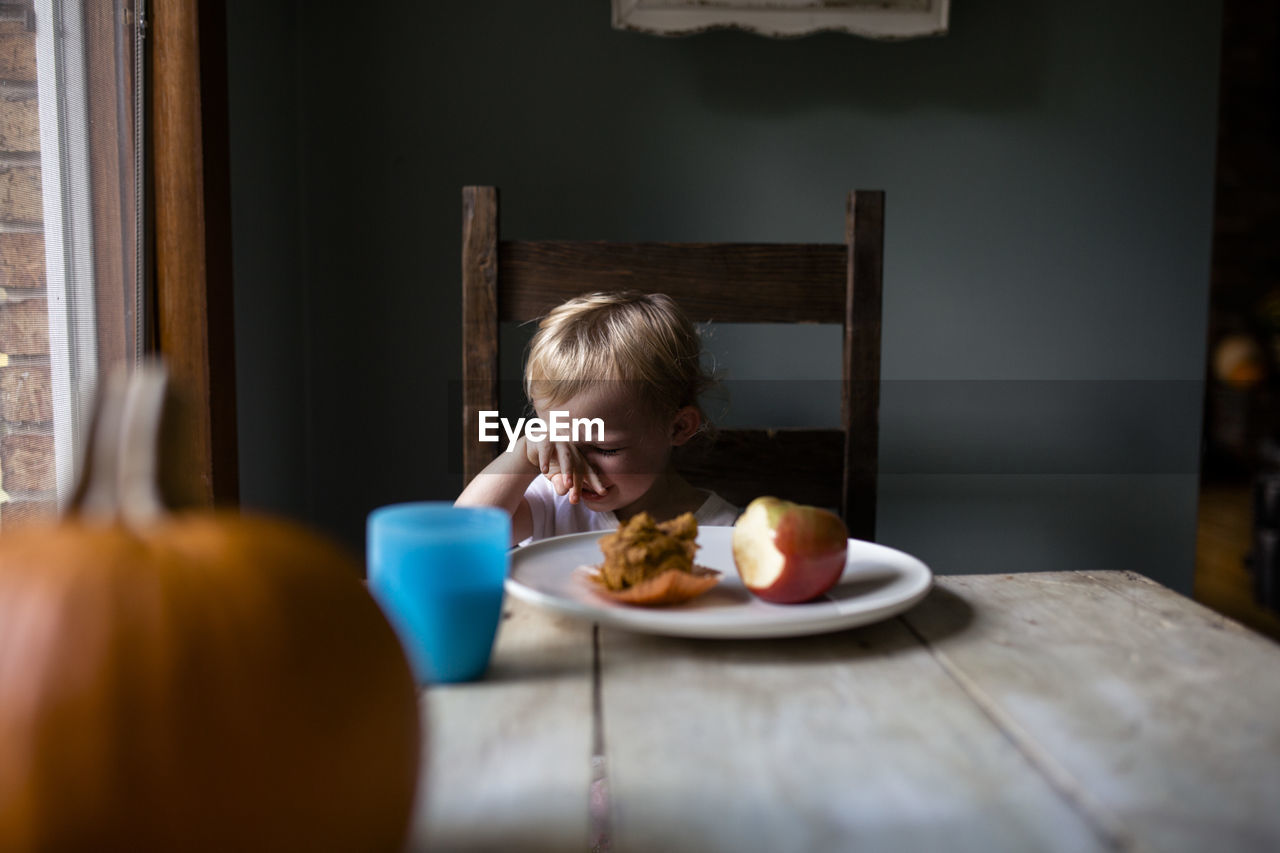 Upset toddler eating a snack at the table
