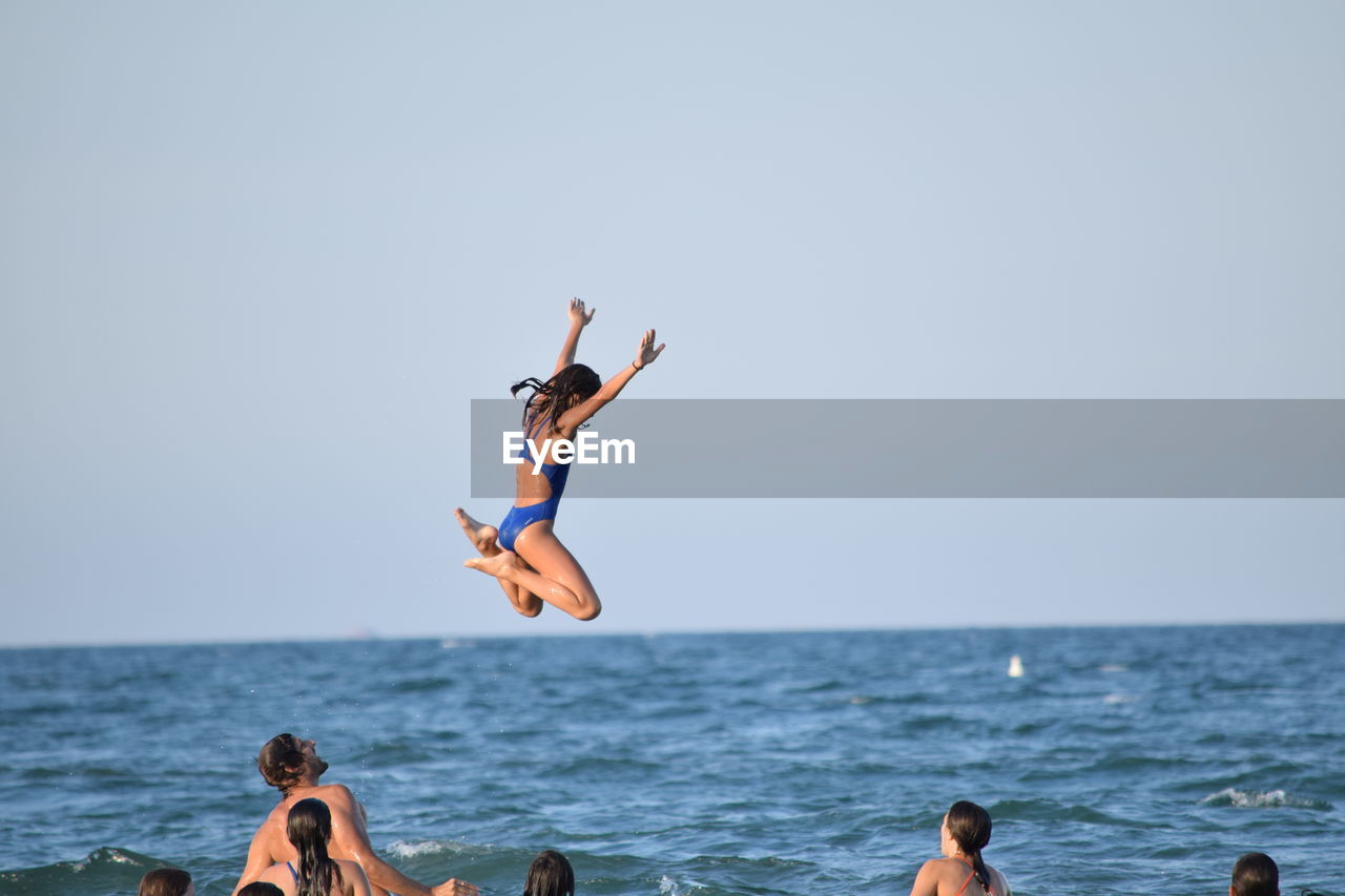 People enjoying in sea against clear sky