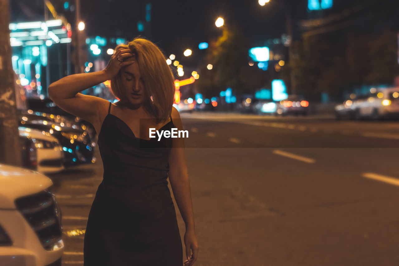 Woman standing on road at night