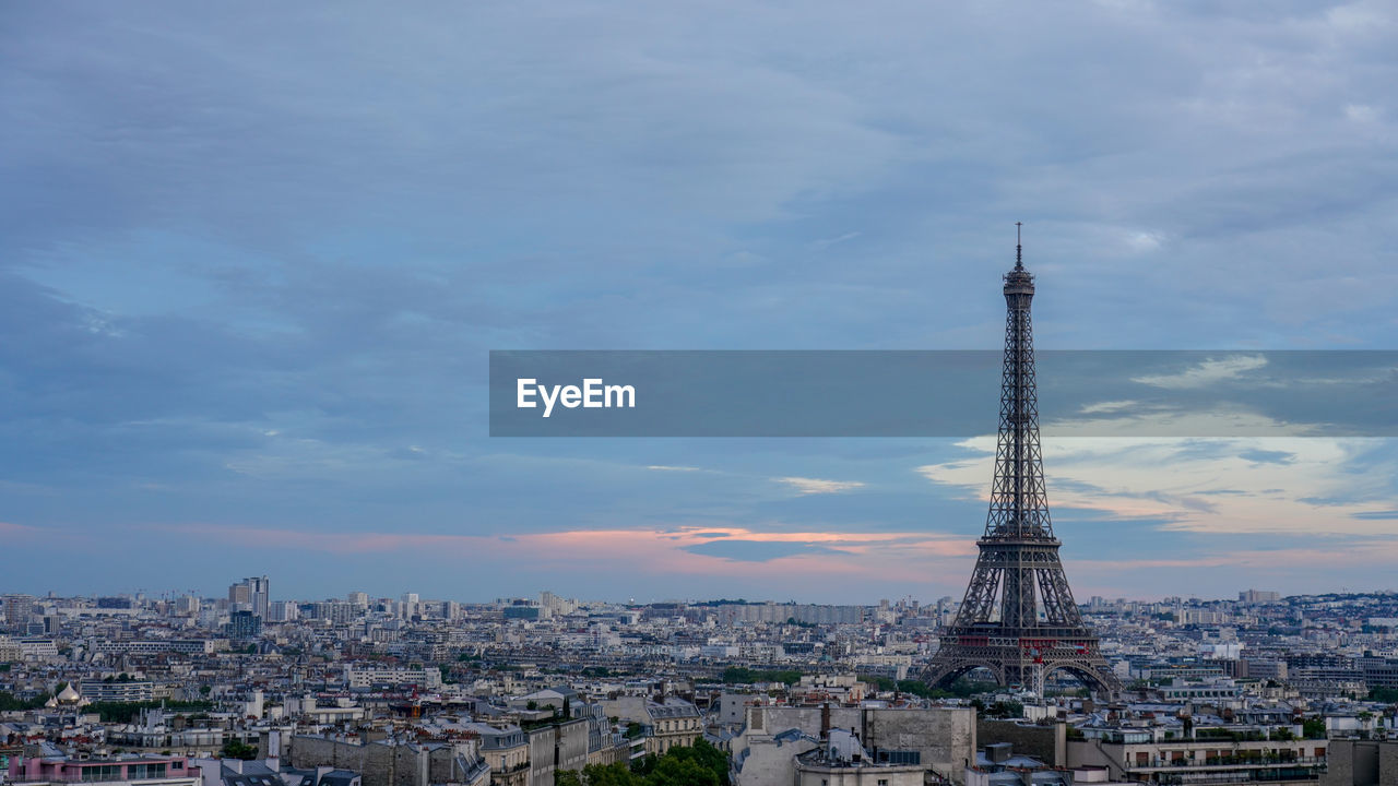 Aerial view of buildings and eiffel tower in city against cloudy sky