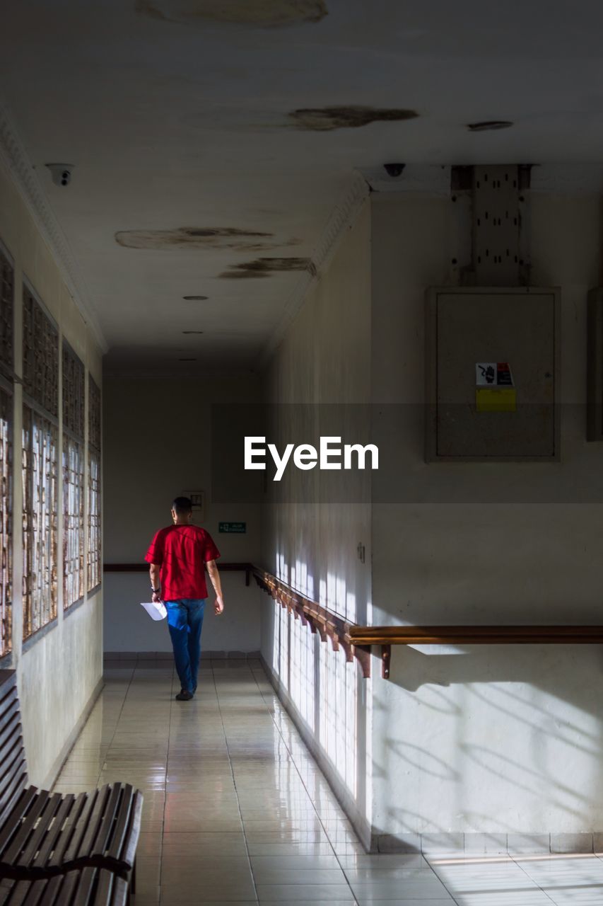 Rear view of man walking in corridor of building