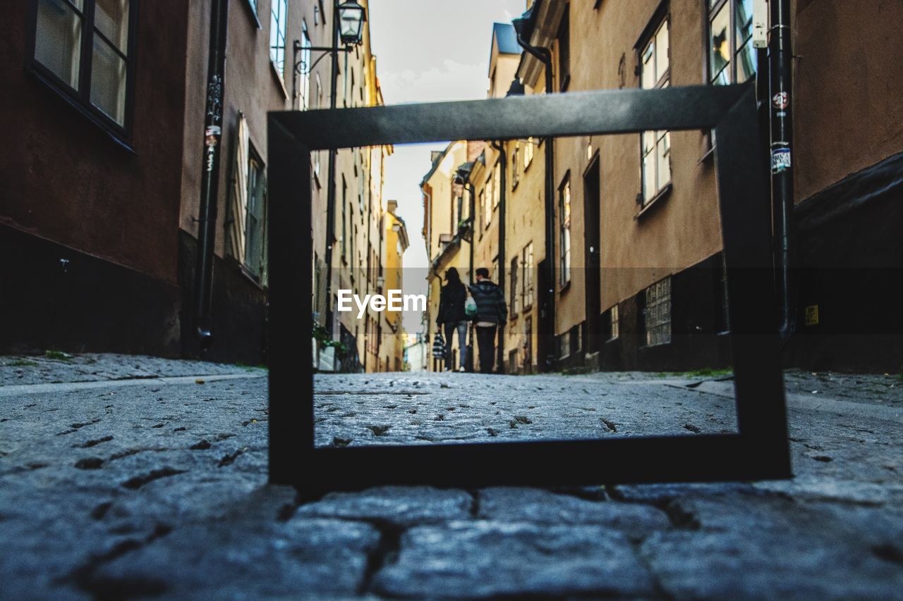 Low angle view of man and woman seen through frame on street