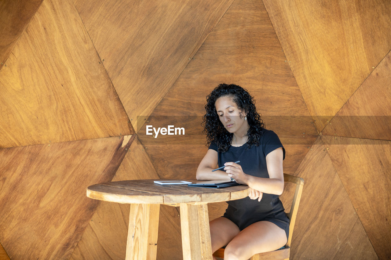 Woman using a digital tablet while sitting at a table.