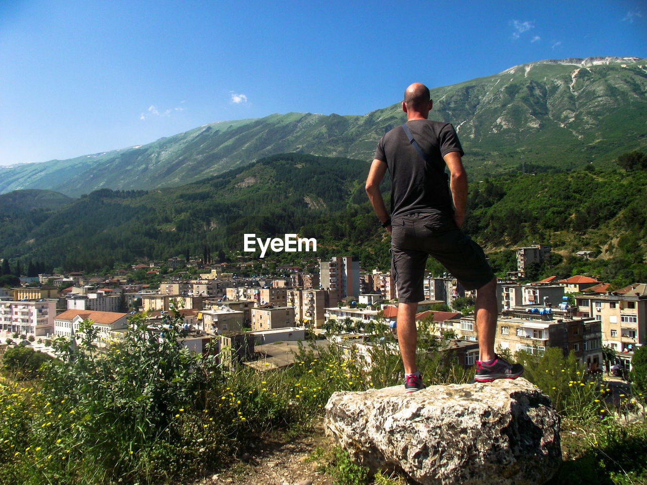 Rear view of hiker standing on rock against mountains