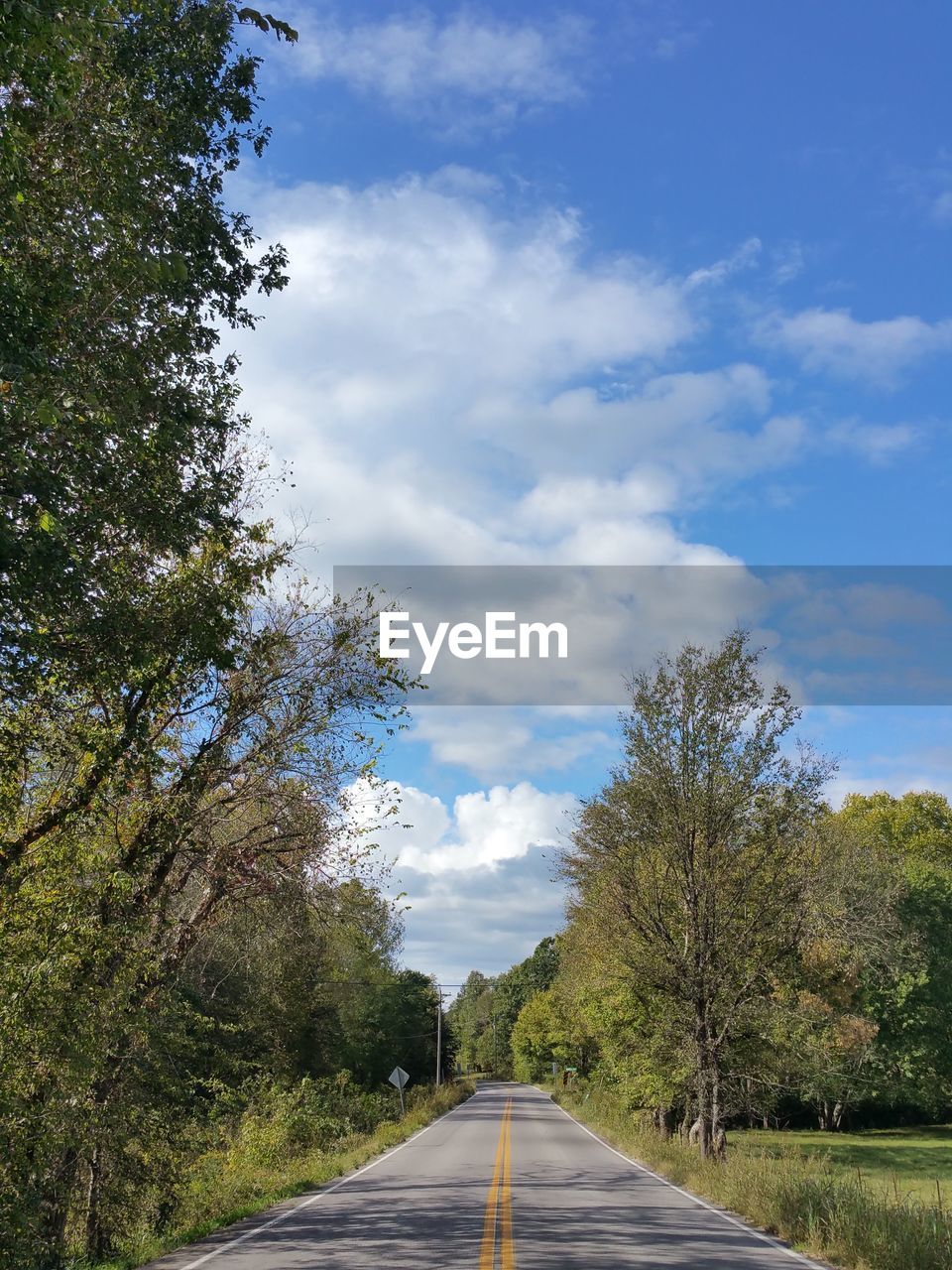 ROAD ALONG TREES AND LANDSCAPE AGAINST SKY