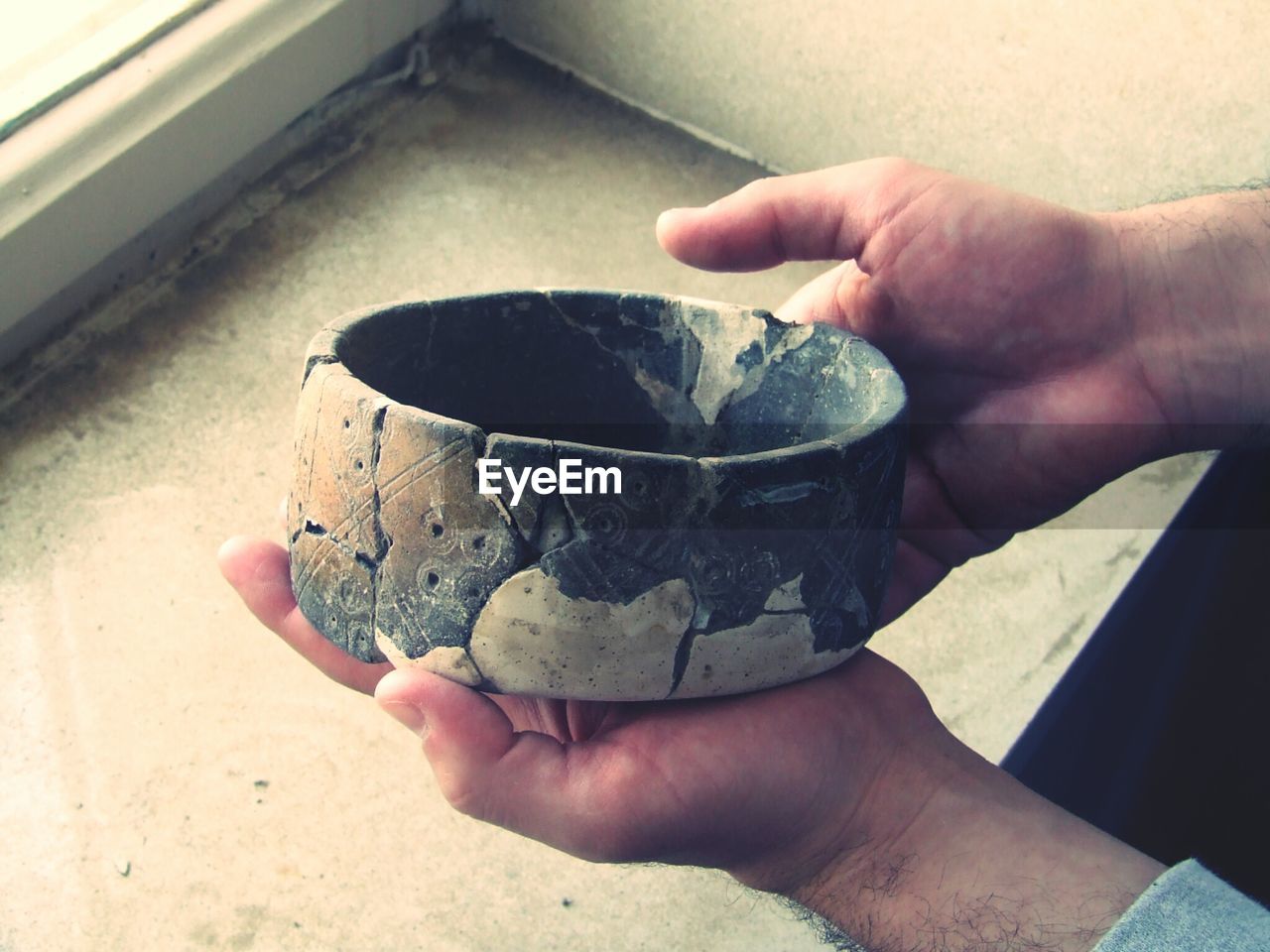 Cropped image of man holding pot at window