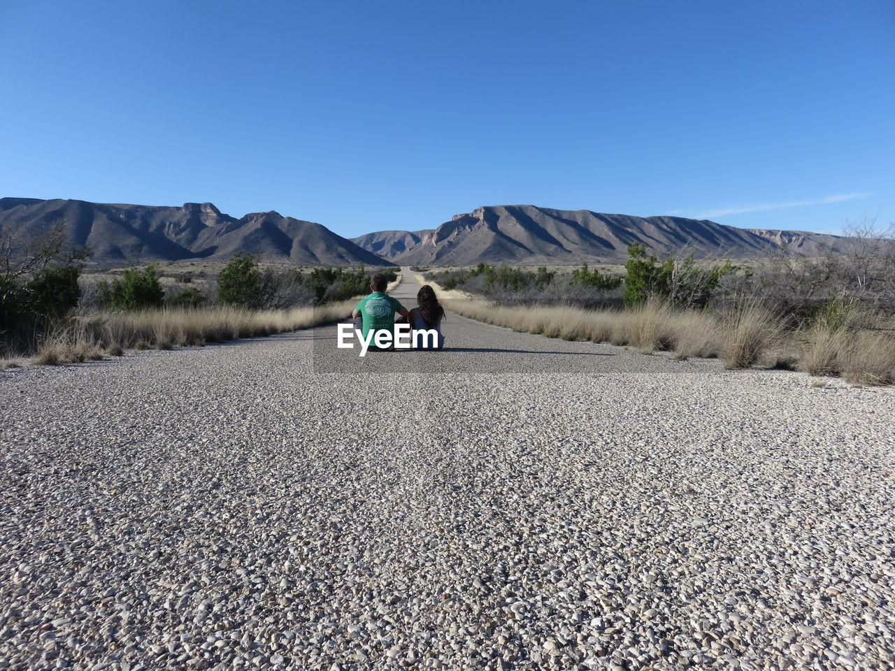 REAR VIEW OF WOMAN STANDING ON ROAD