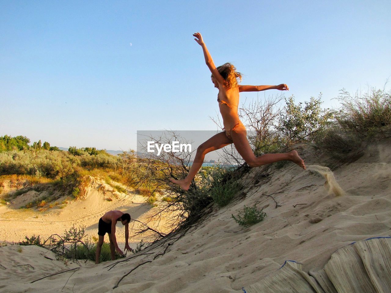 Young woman jumping on beach against clear sky