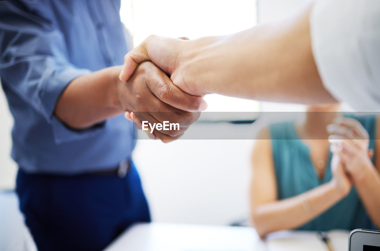 midsection of business colleagues shaking hands