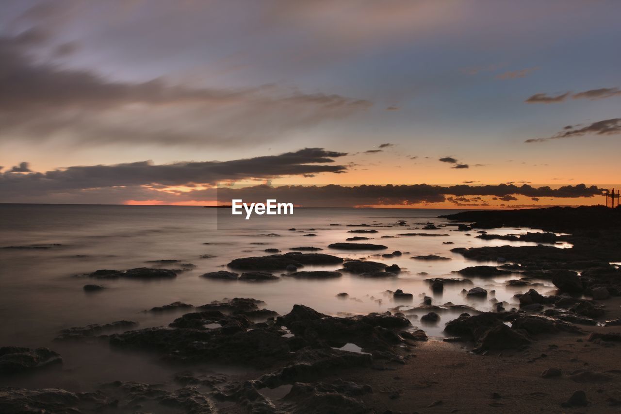 Scenic view of sea and shore against sky during sunset