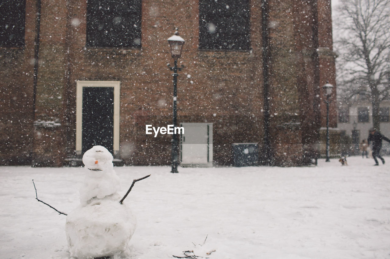 Snowman on field against building