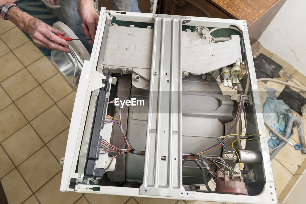 Middle aged man repairing broken washing machine with tools, household chores