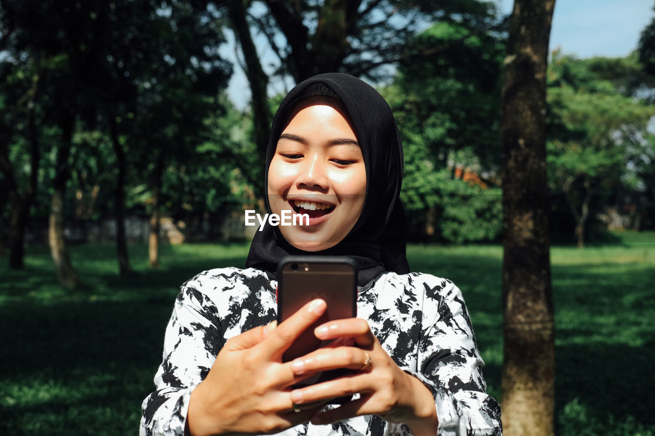 Young woman using mobile phone in park