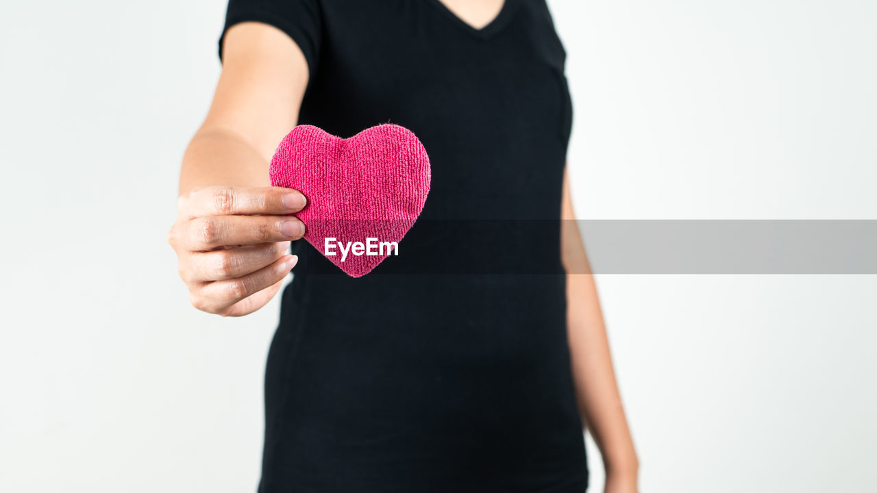 MIDSECTION OF WOMAN HOLDING HEART SHAPE WITH HANDS