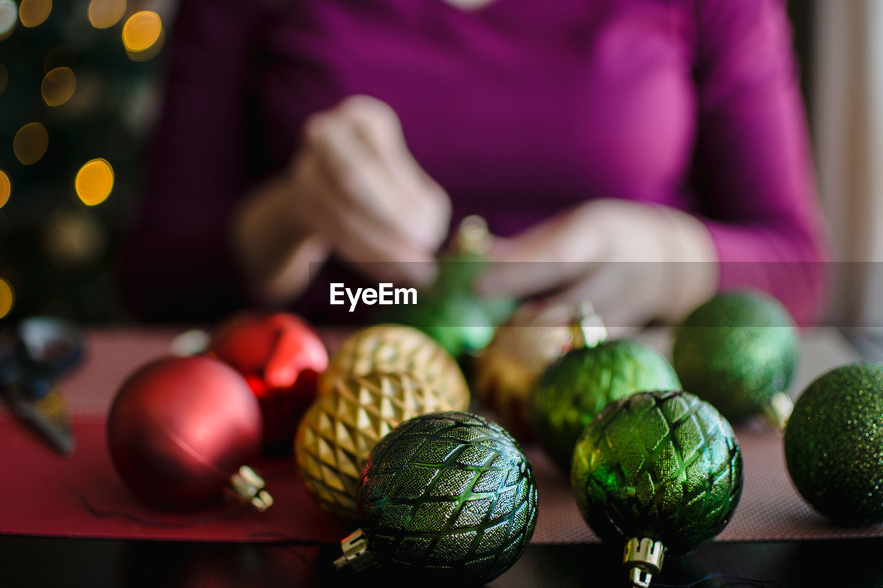 Midsection of woman preparing baubles on table