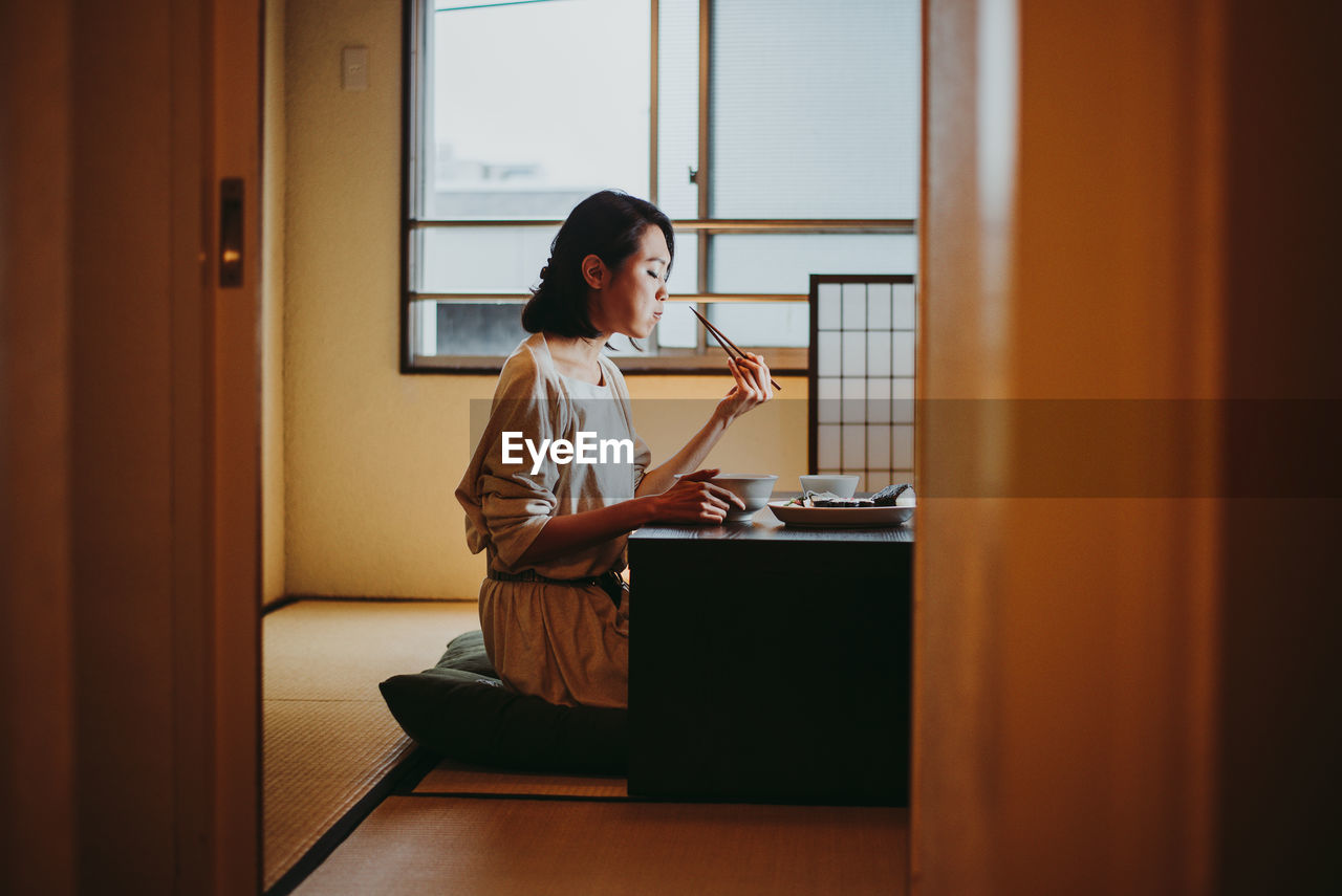 Young woman sitting on table at home