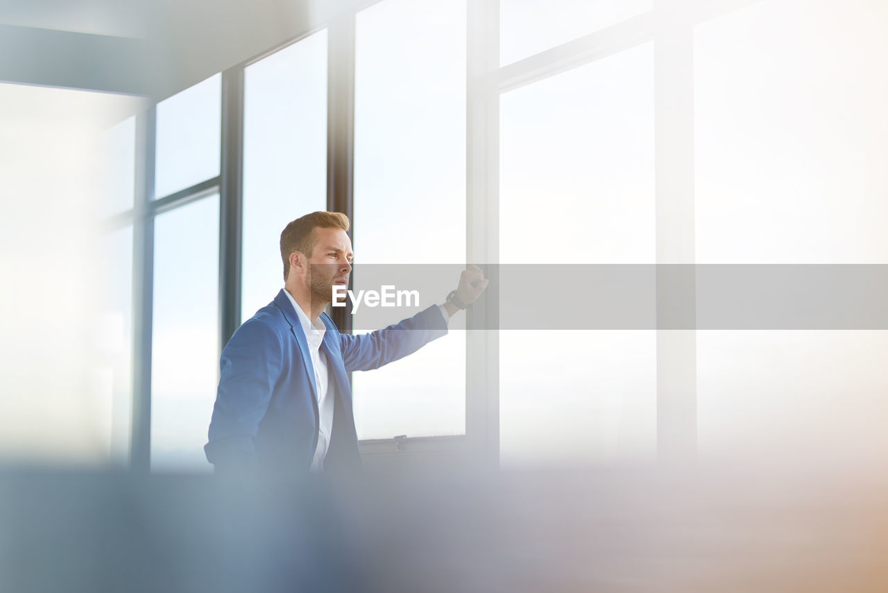 Thoughtful businessman wearing suit while standing at office