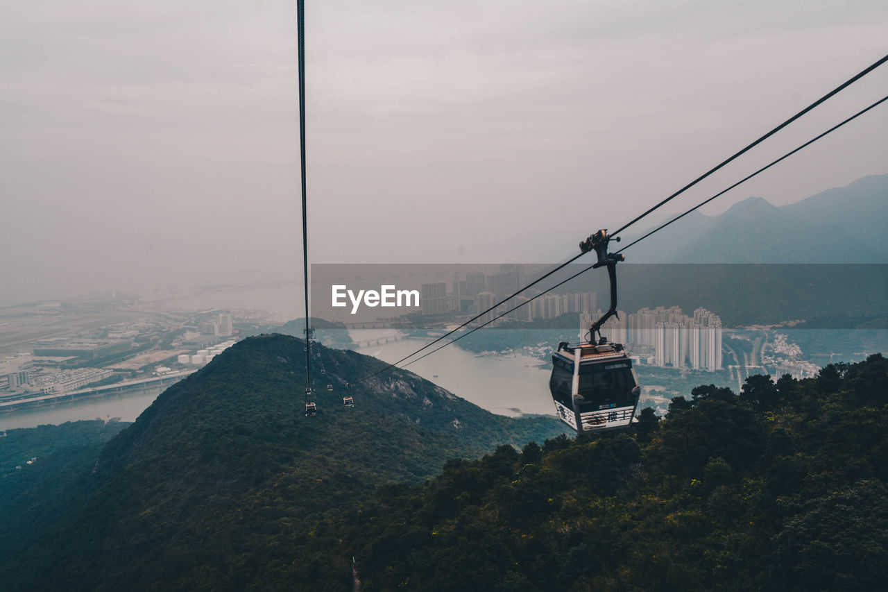 Overhead cable car over mountains against sky