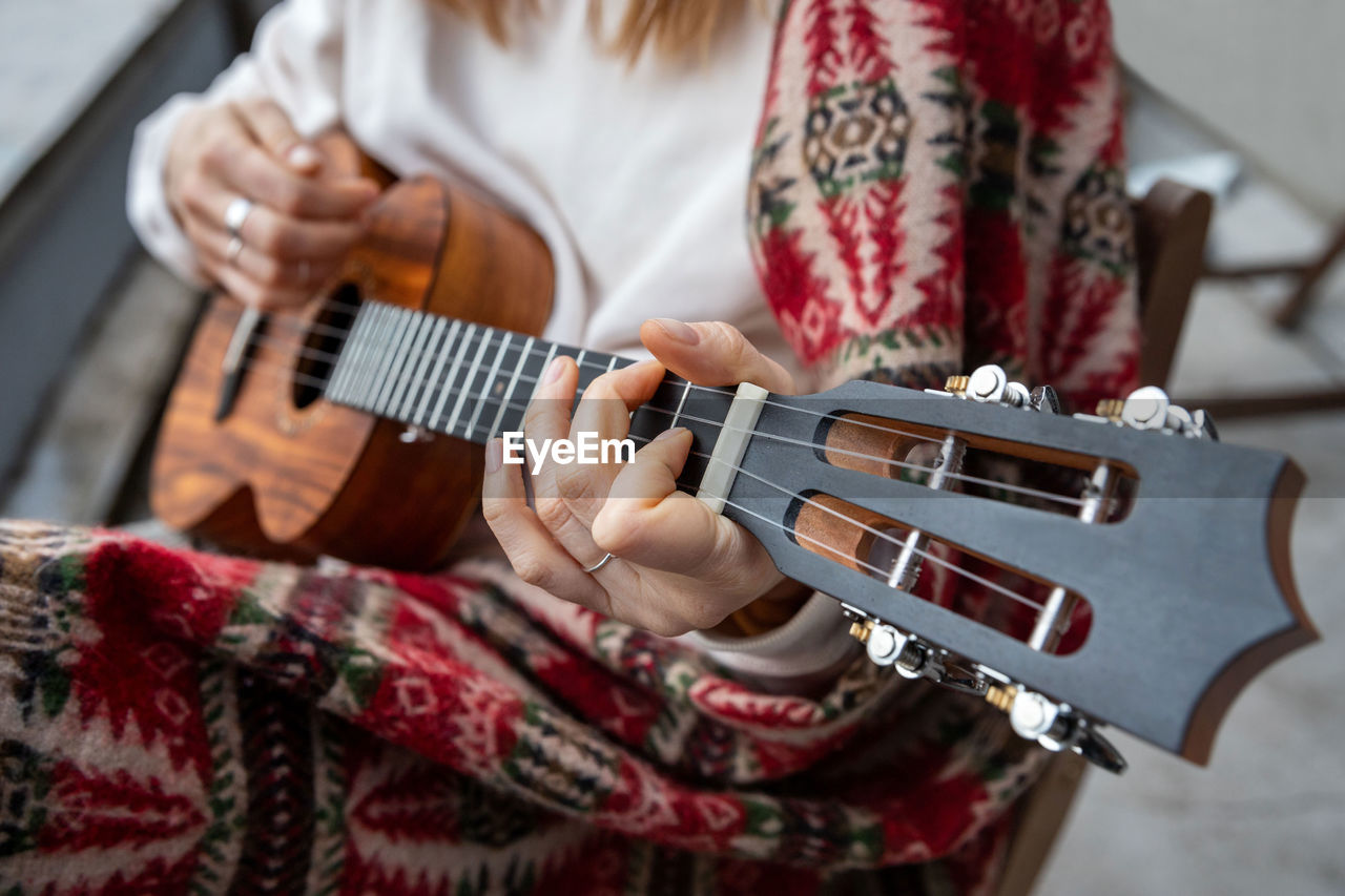 Midsection of woman playing guitar