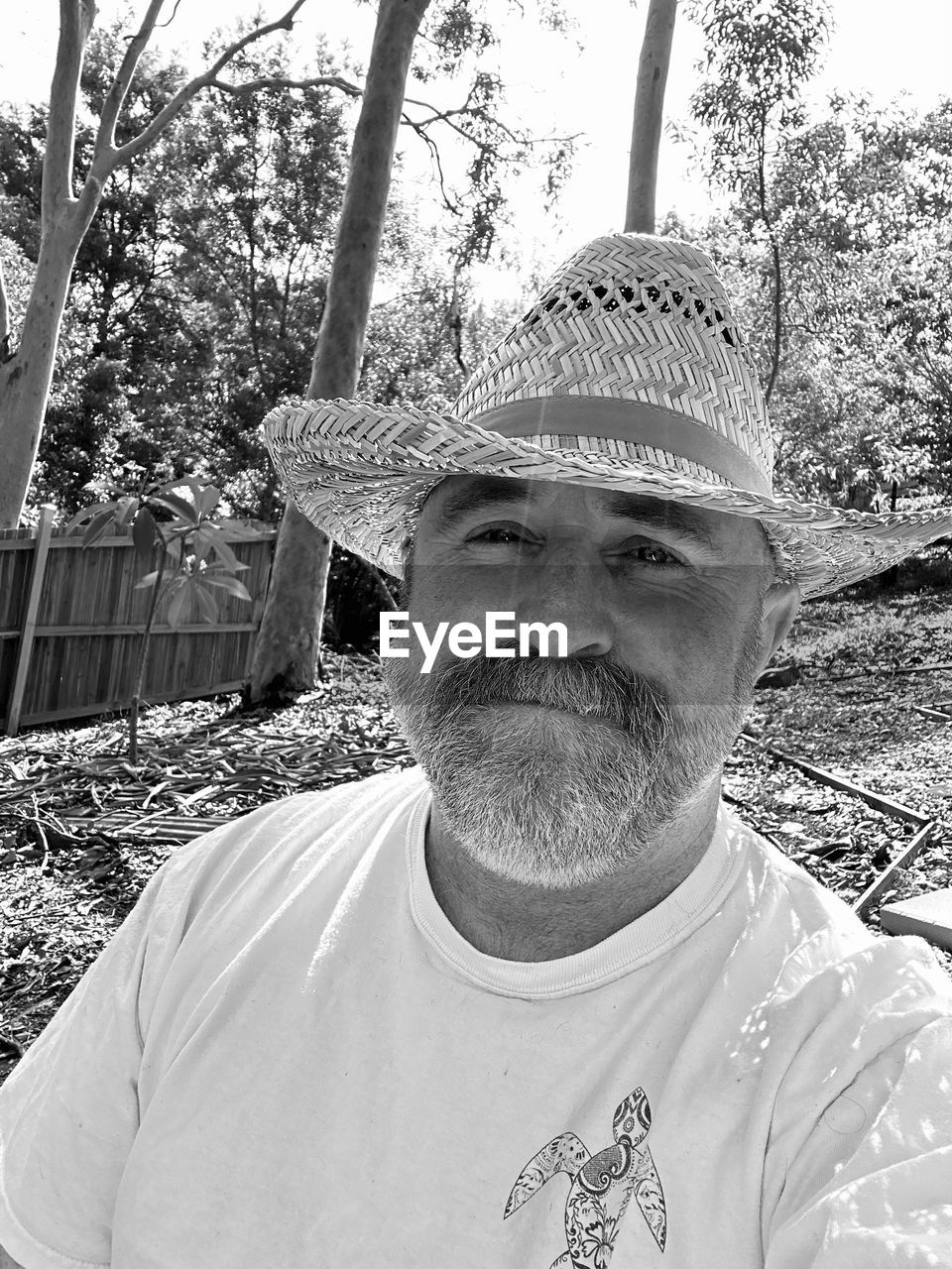 portrait, one person, front view, adult, men, looking at camera, headshot, day, hat, black and white, tree, lifestyles, white, facial hair, person, leisure activity, beard, casual clothing, plant, nature, monochrome photography, human face, mature adult, clothing, outdoors, monochrome, smiling, standing, sun hat