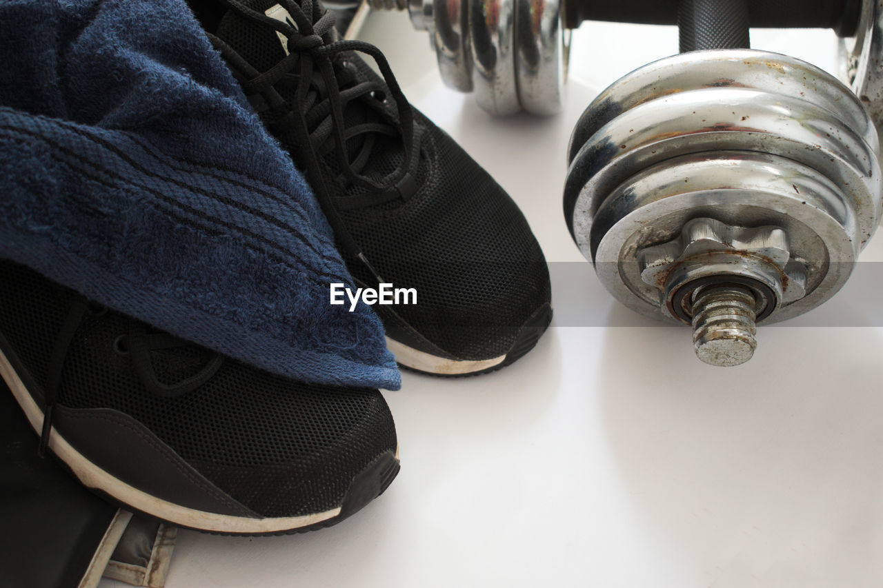 High angle view of sports shoe with dumbbell on floor