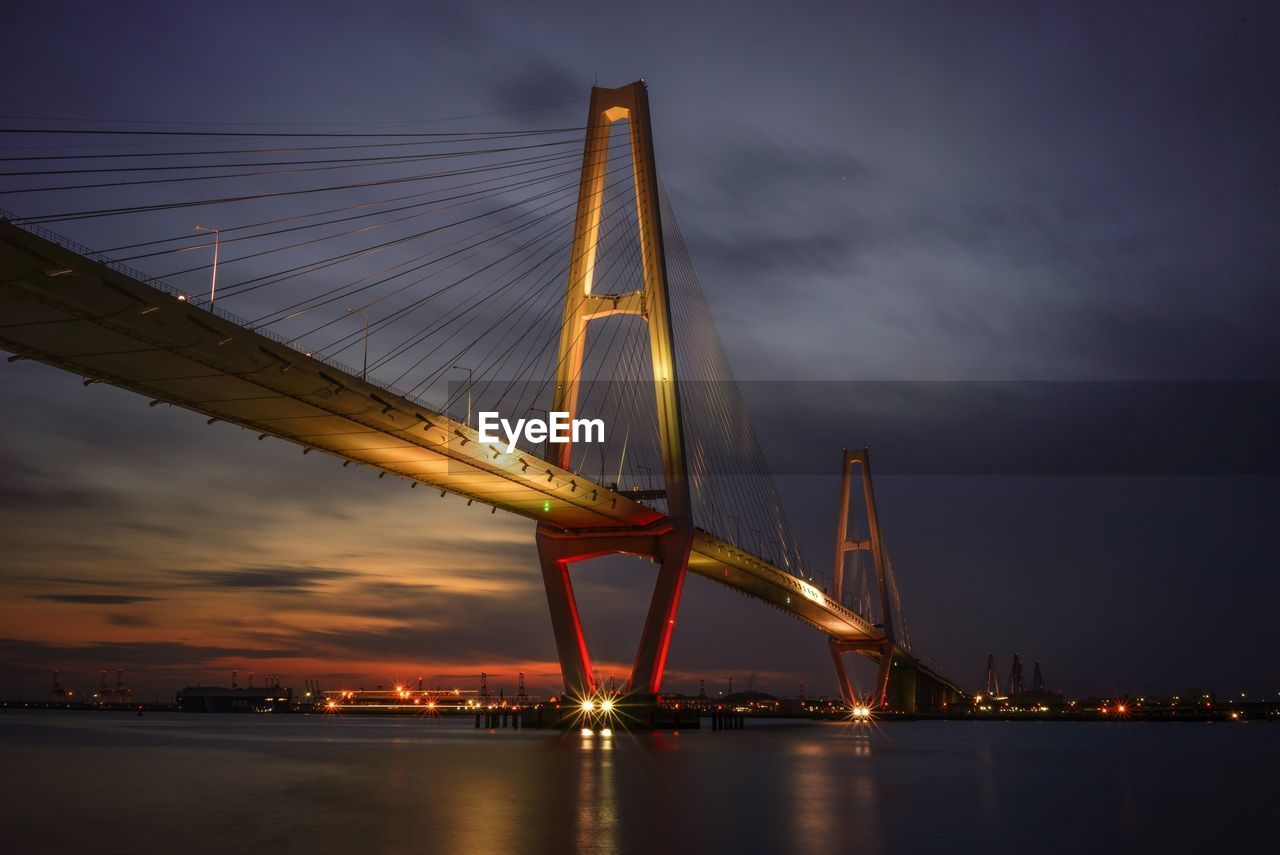 SUSPENSION BRIDGE OVER RIVER AT NIGHT