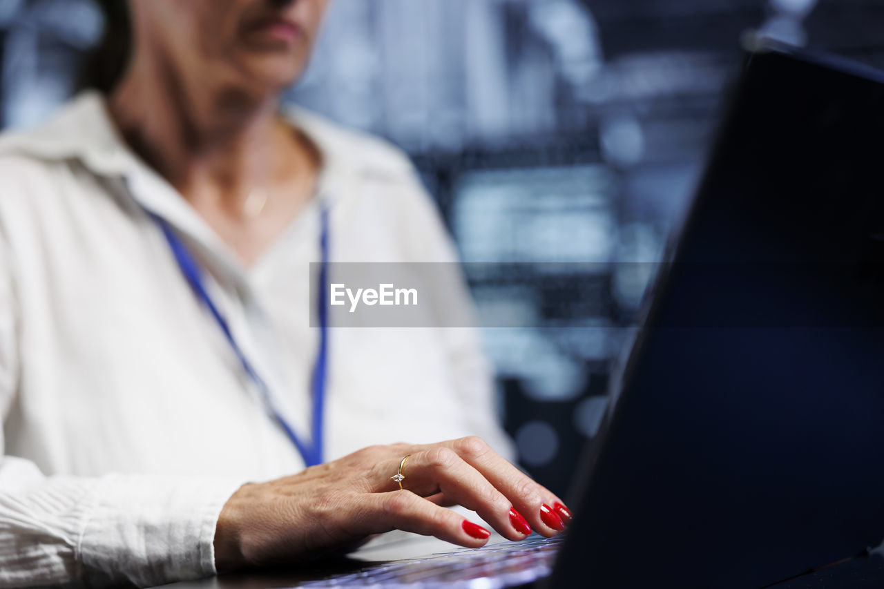 midsection of woman using laptop while sitting on table