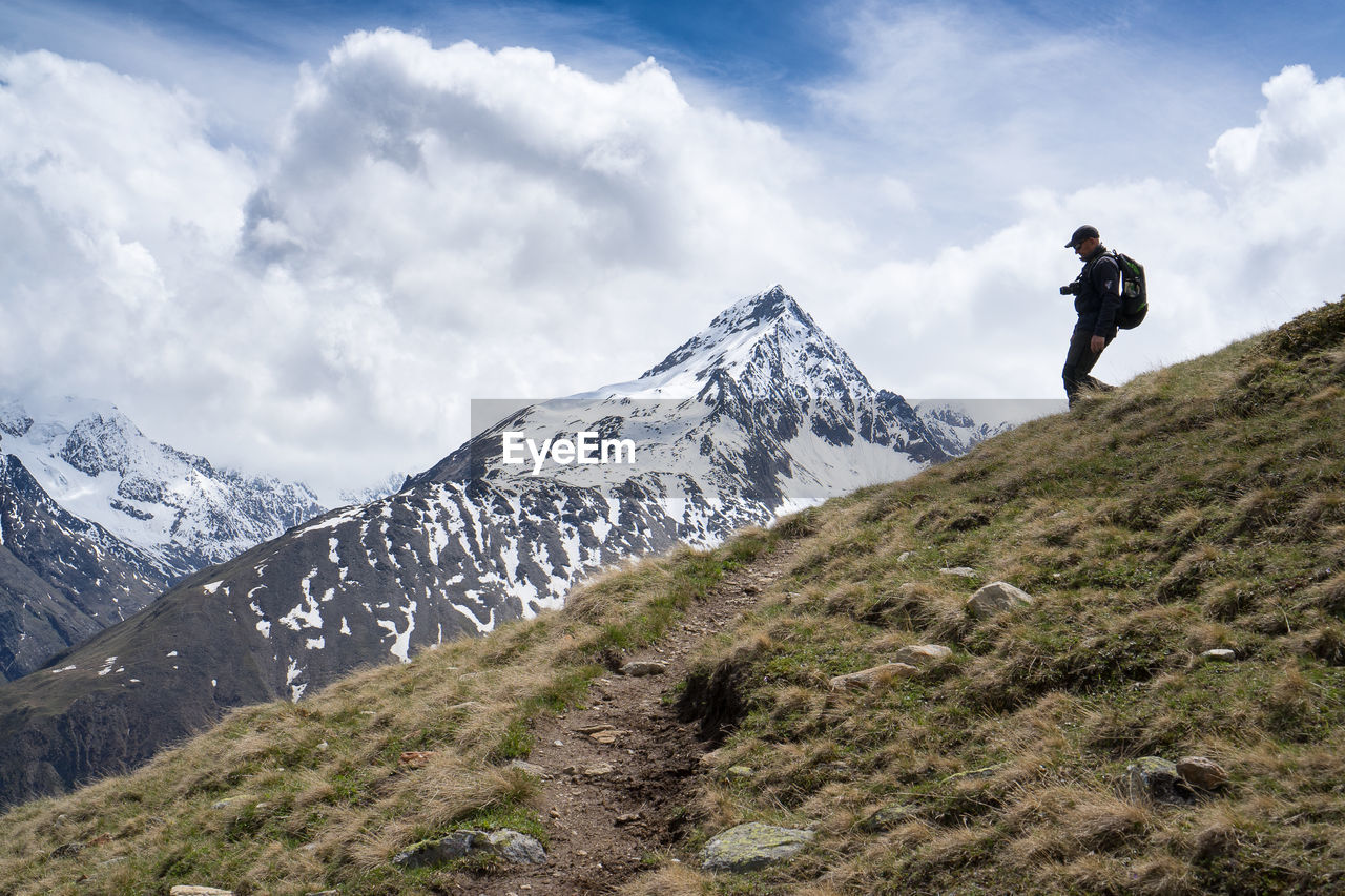 Man standing on snowcapped mountain against sky