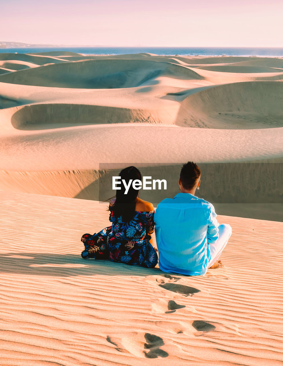 rear view of woman sitting on sand at beach