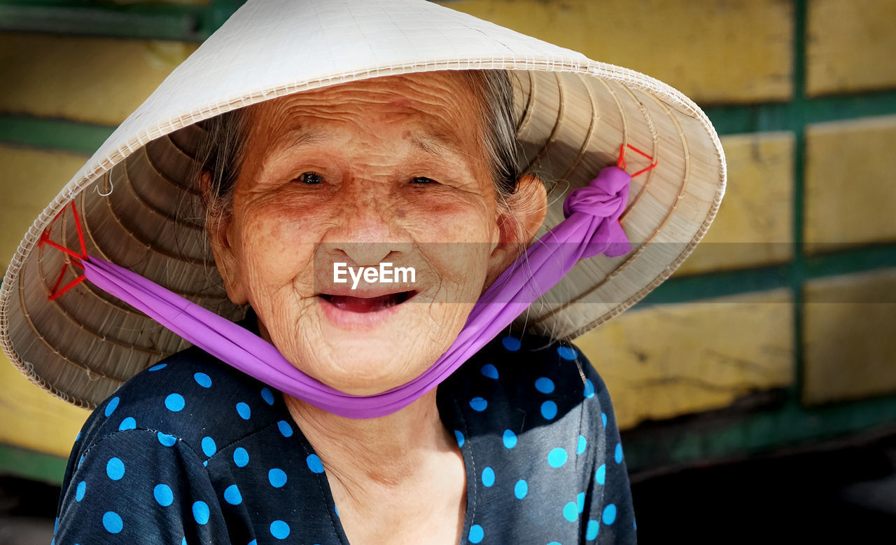 Portrait of smiling senior woman wearing asian style conical hat