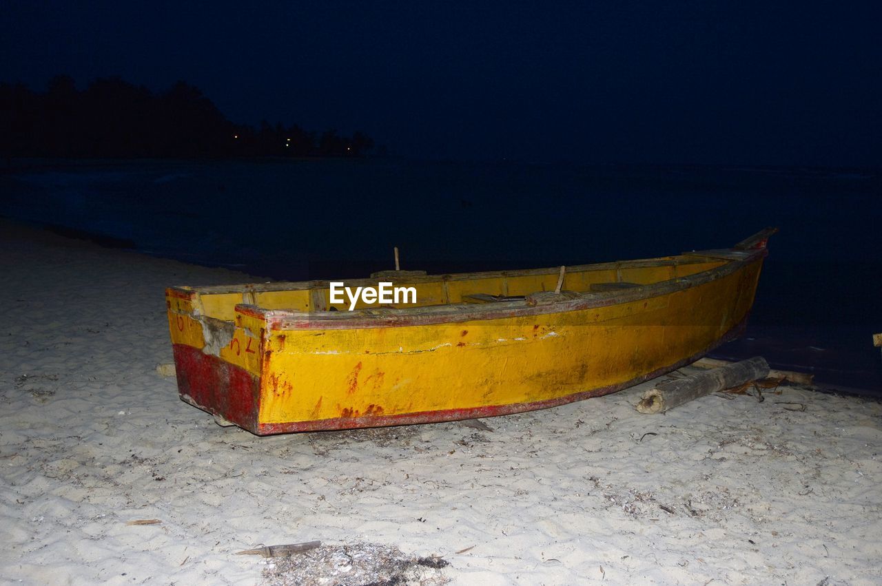 Boat moored on beach against sky