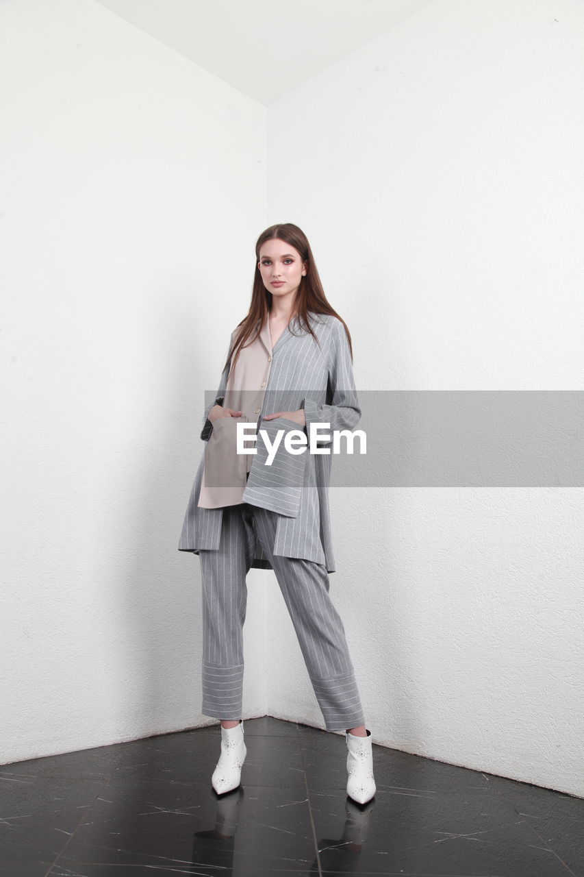 Young woman standing against white wall