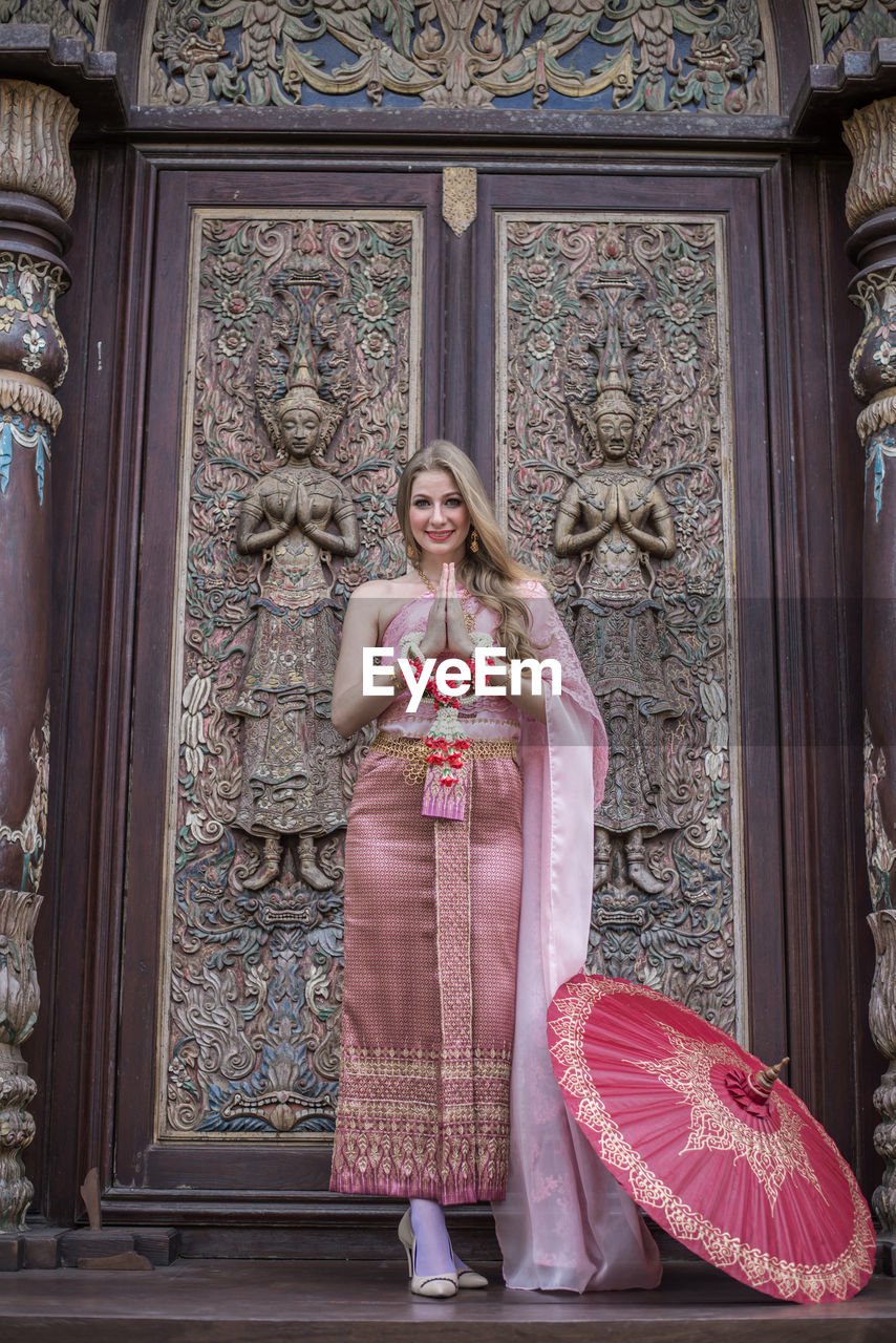 Full length of woman standing against temple door