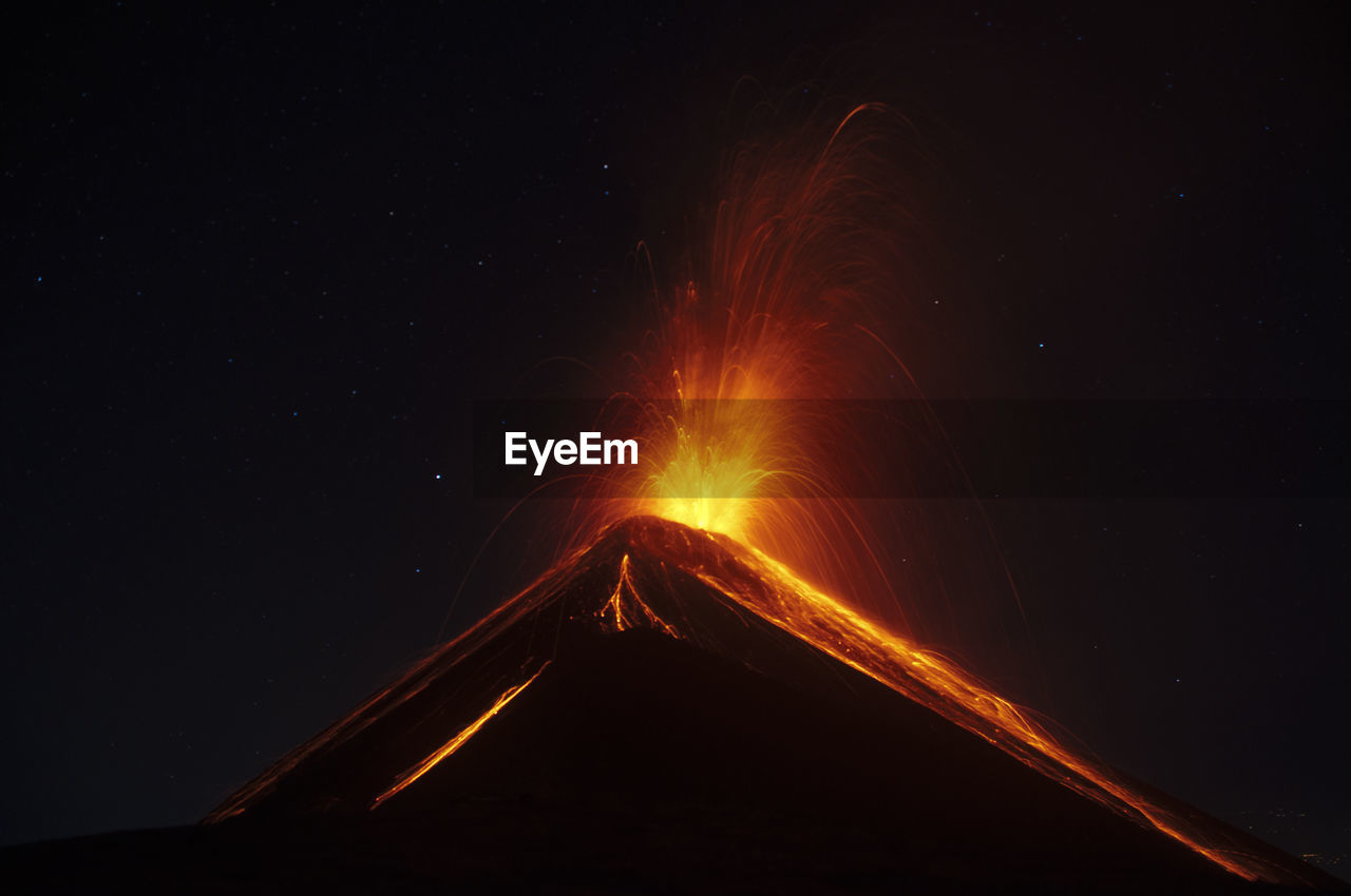 Volcano eruption in the dark with stars sky on the background