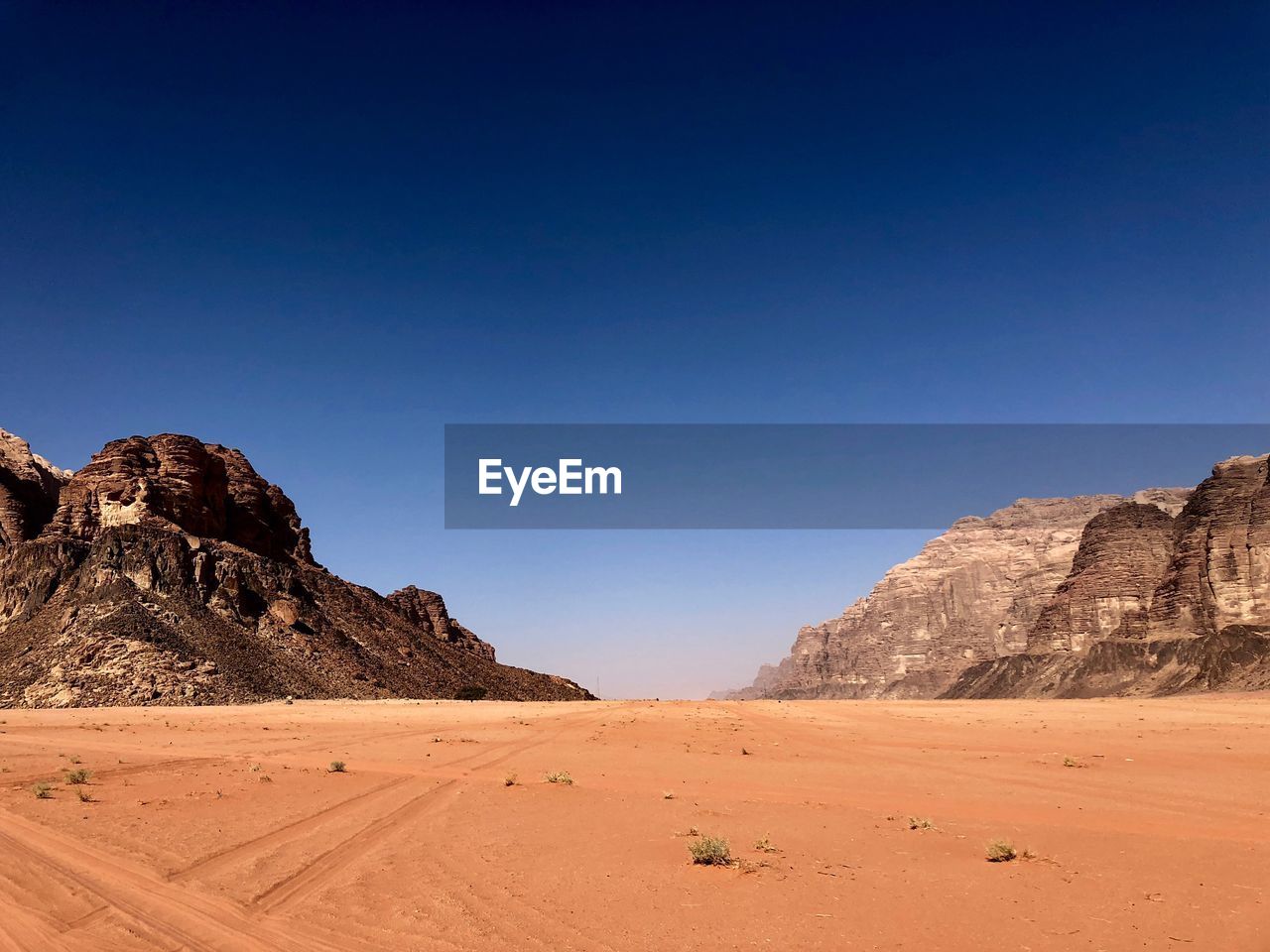 Scenic view of desert against clear blue sky