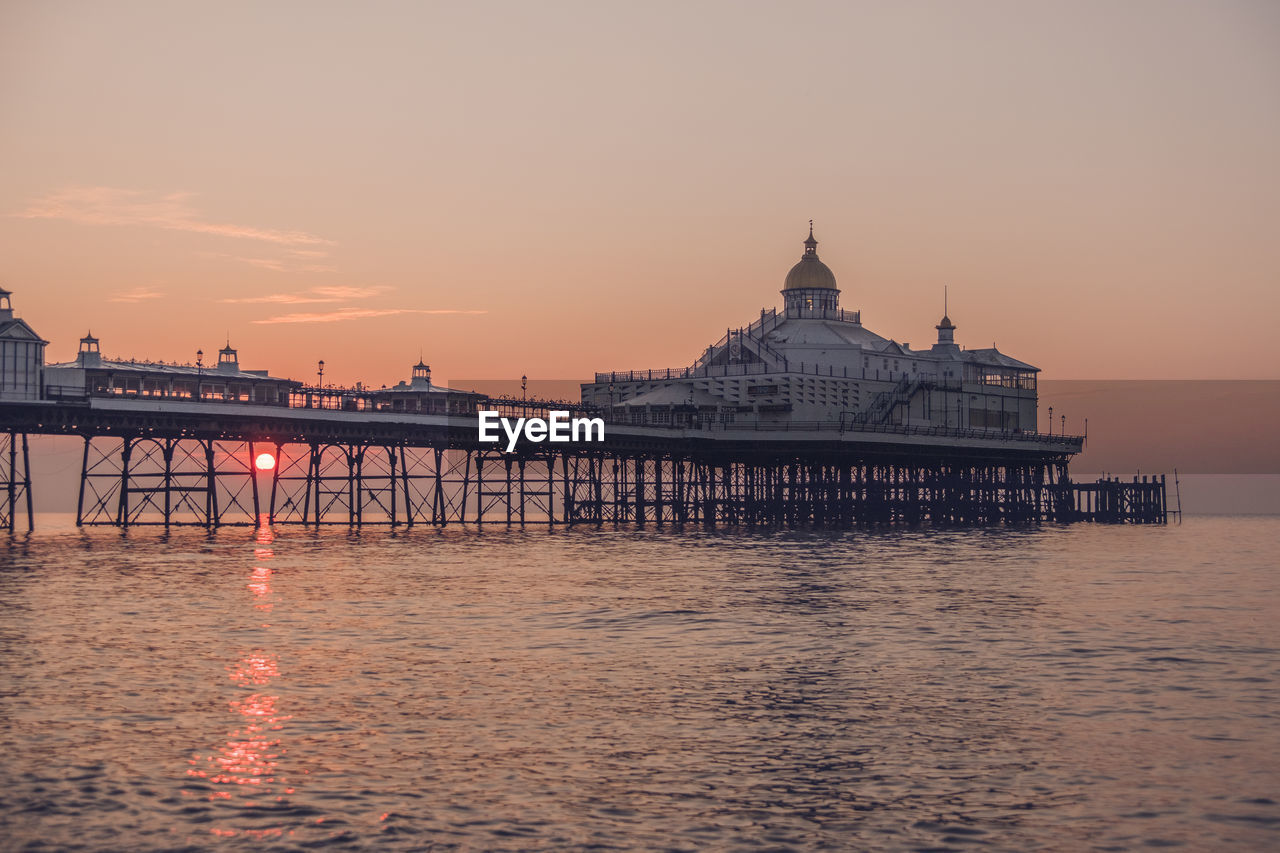 Eastbourne seafront at sunrise with calm sea and clear skies.