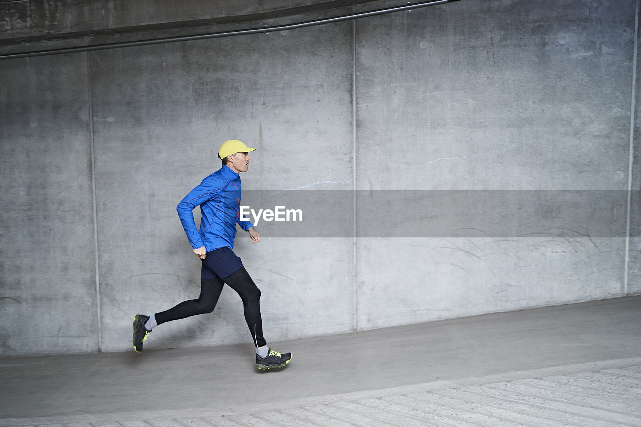 Mature man jogging in parking garage of residential building