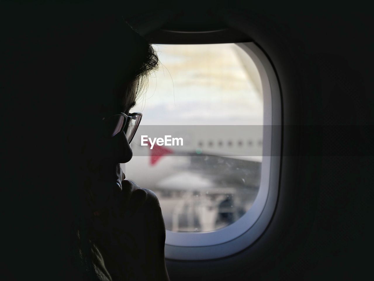 MAN LOOKING AT AIRPLANE SEEN THROUGH WINDOW