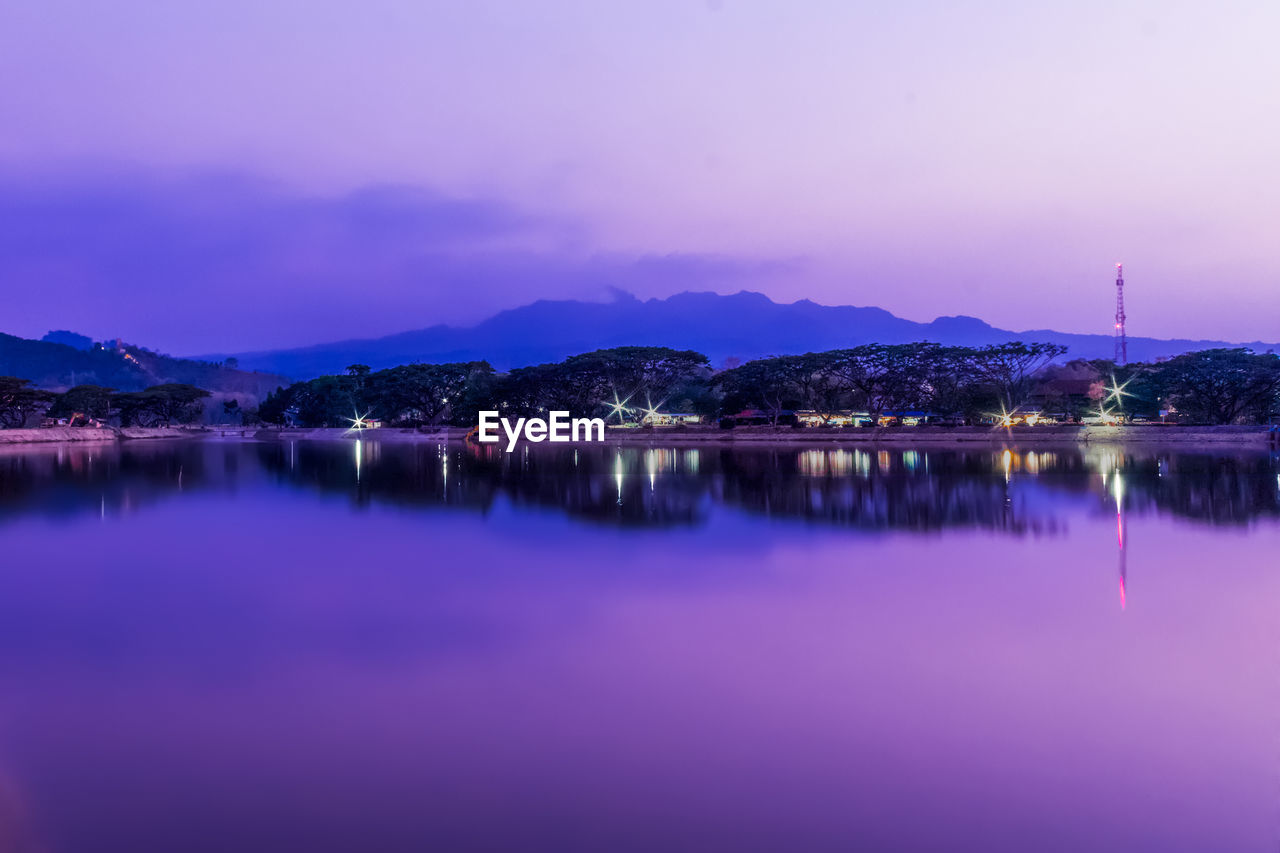 reflection, sky, water, waterfront, lake, beauty in nature, mountain, nature, no people, illuminated, scenics - nature, built structure, architecture, building exterior, purple, tranquility, tranquil scene, dusk, sunset, outdoors