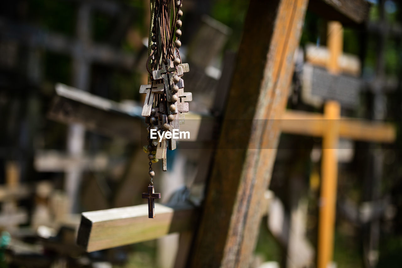 Close-up of bead necklaces against cross at cemetery